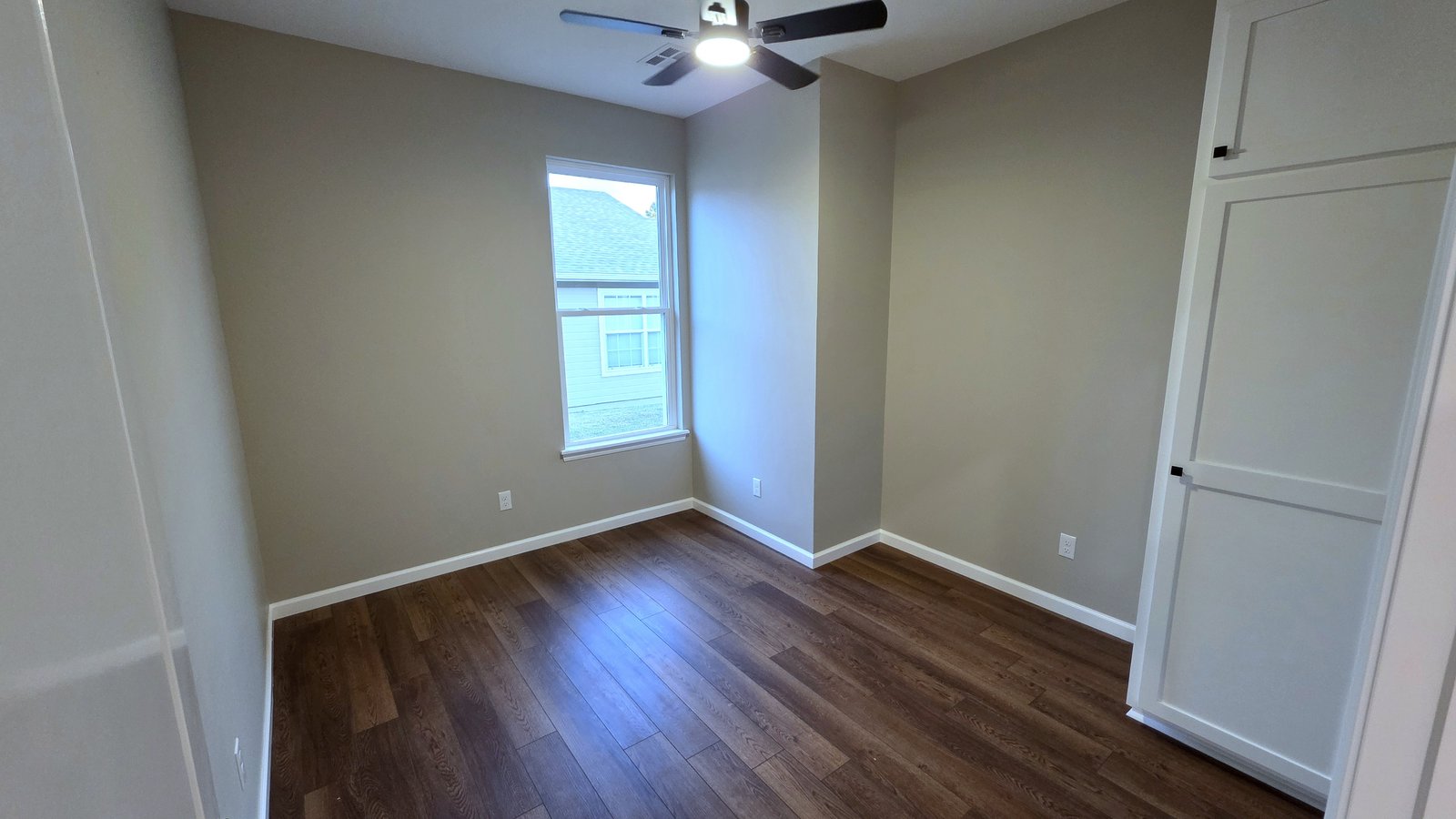 Empty finished bedroom with hardwood floors, ceiling fan, and closet in a custom home