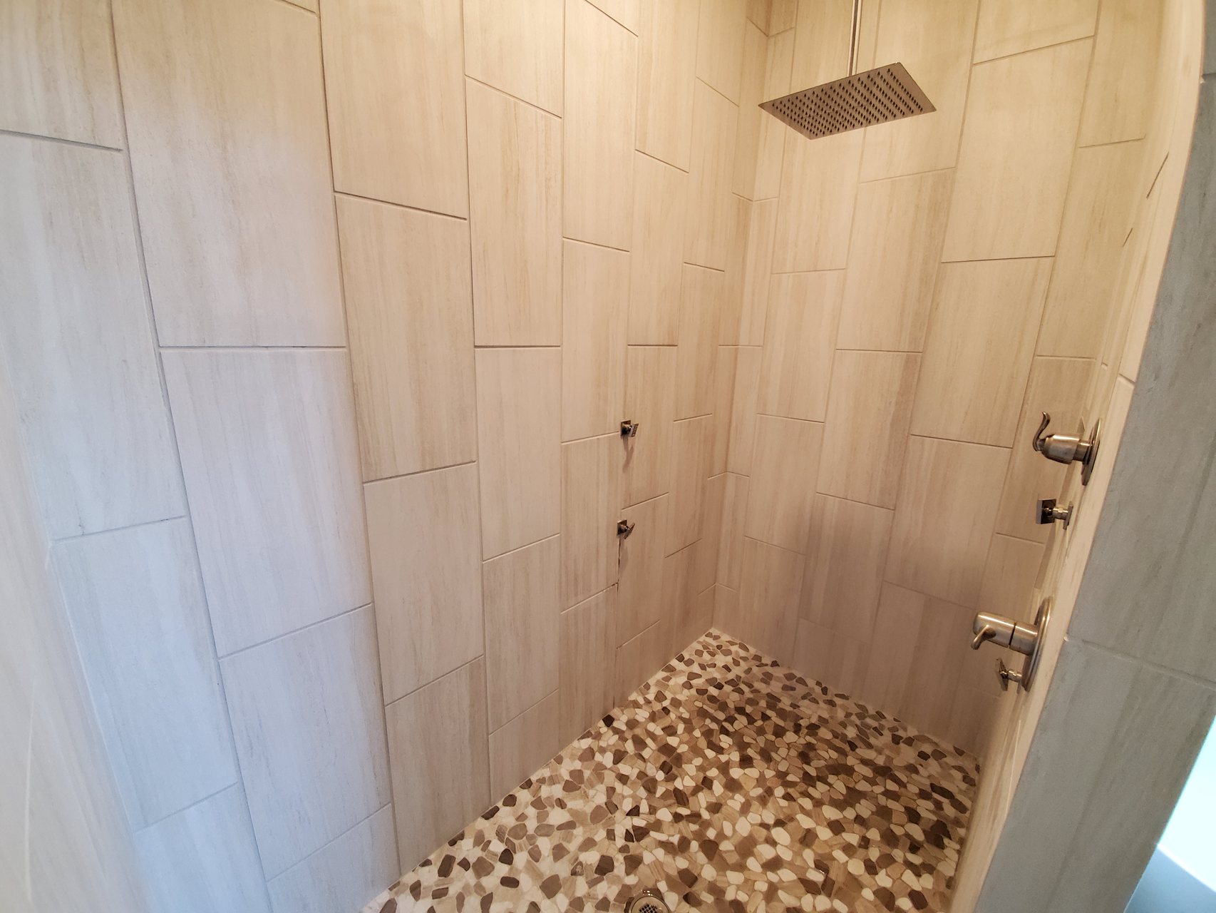 Custom tile shower with rain head and pebble floor