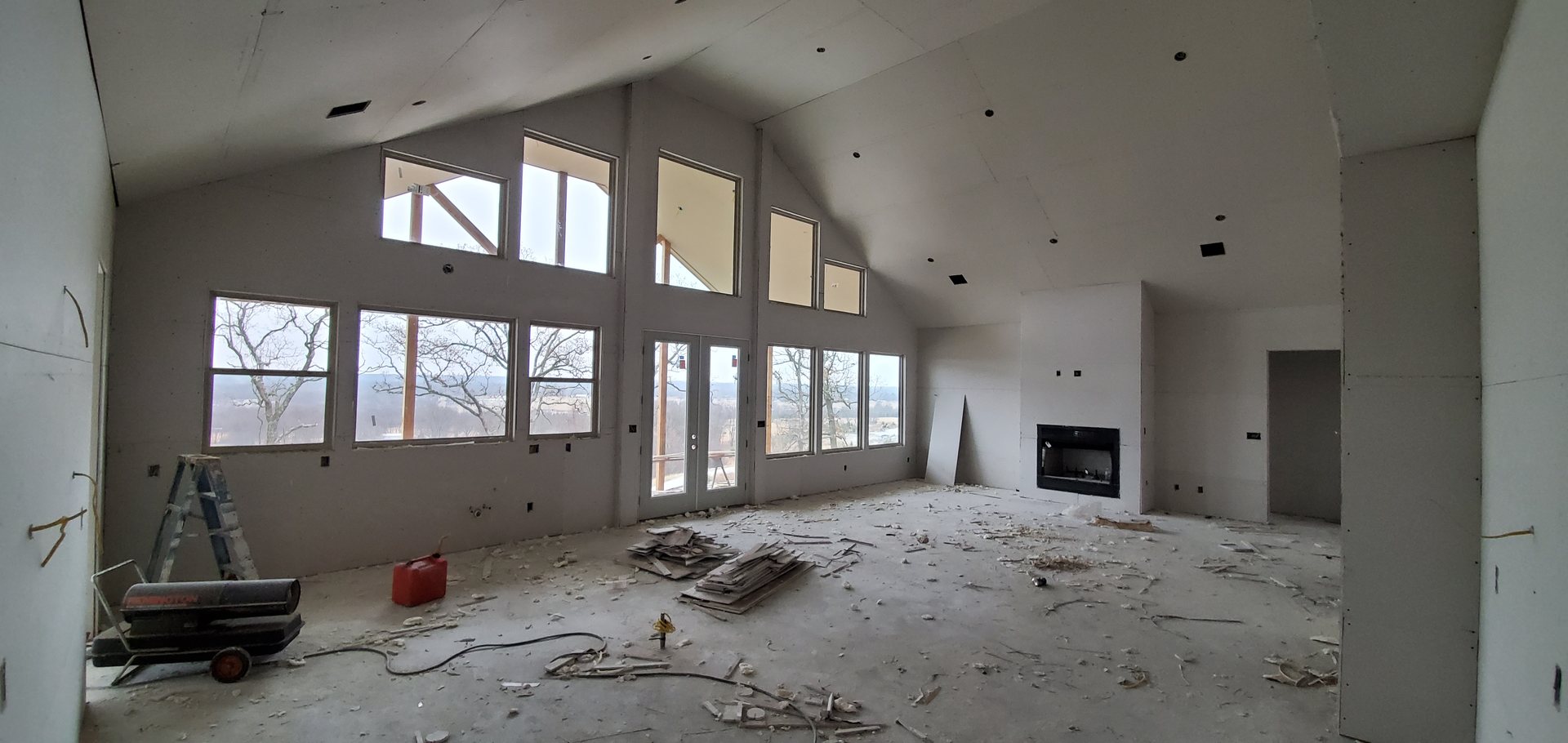 Great room at drywall stage with wall of windows and fireplace niche
