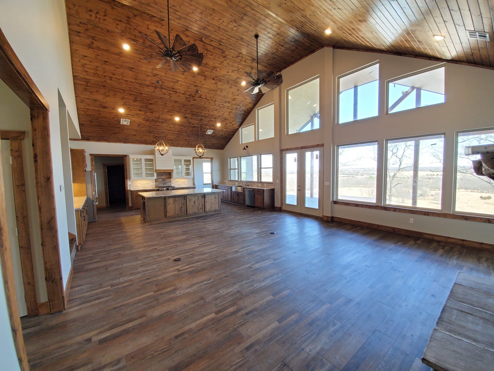 Finished open kitchen and great room with vaulted wood ceiling and large windows