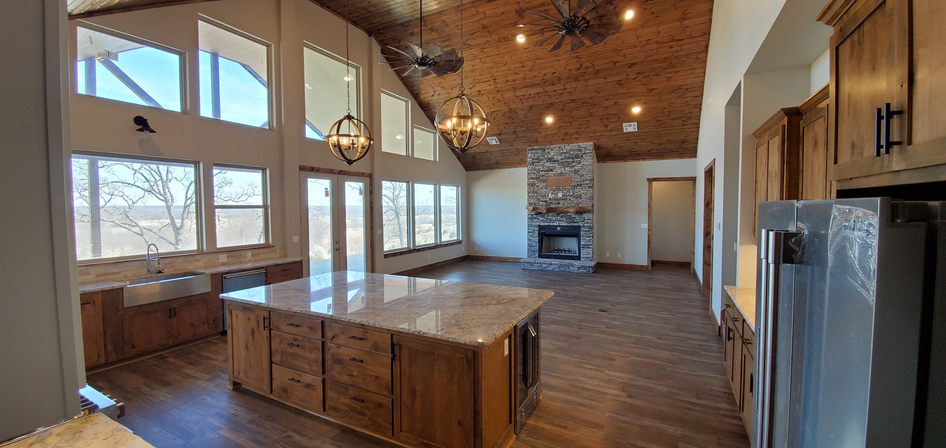 Open kitchen and living with vaulted wood ceiling and wall of windows