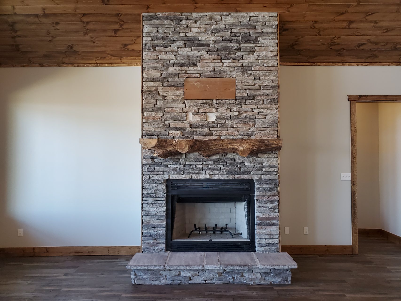 Floor-to-ceiling stacked stone fireplace with live-edge wood mantel