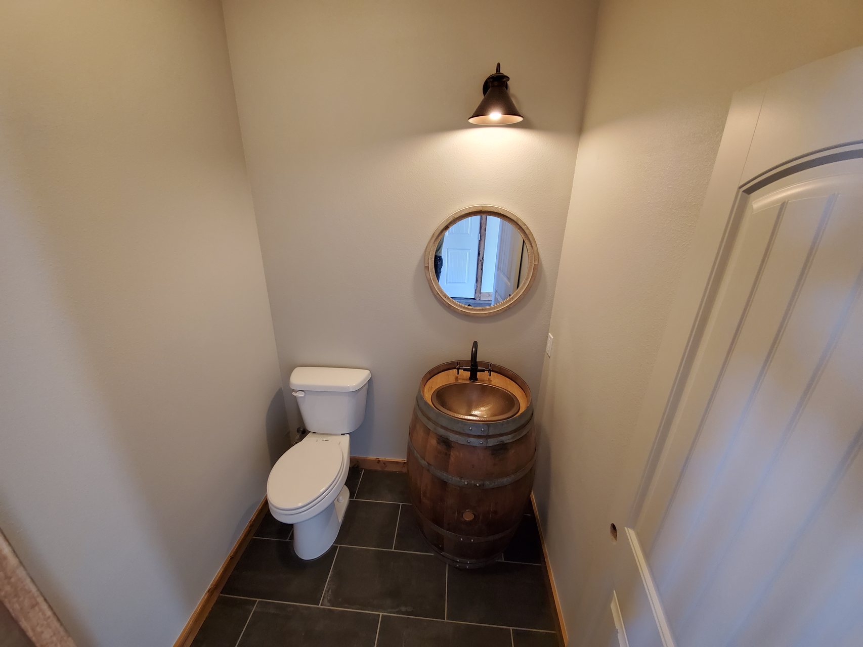 Powder room with custom barrel vanity sink and round mirror