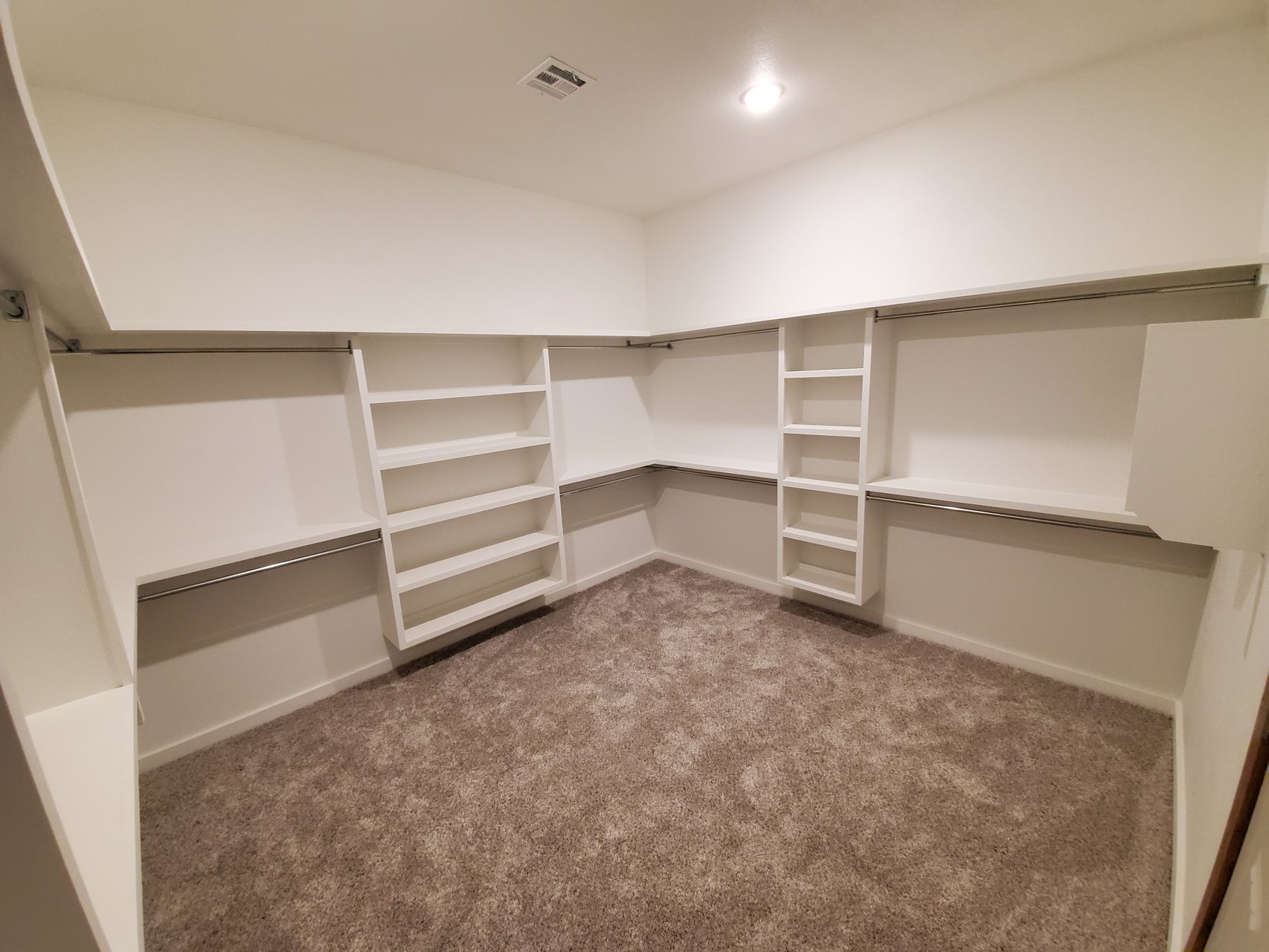 Walk-in closet with white shelving and hanging rods